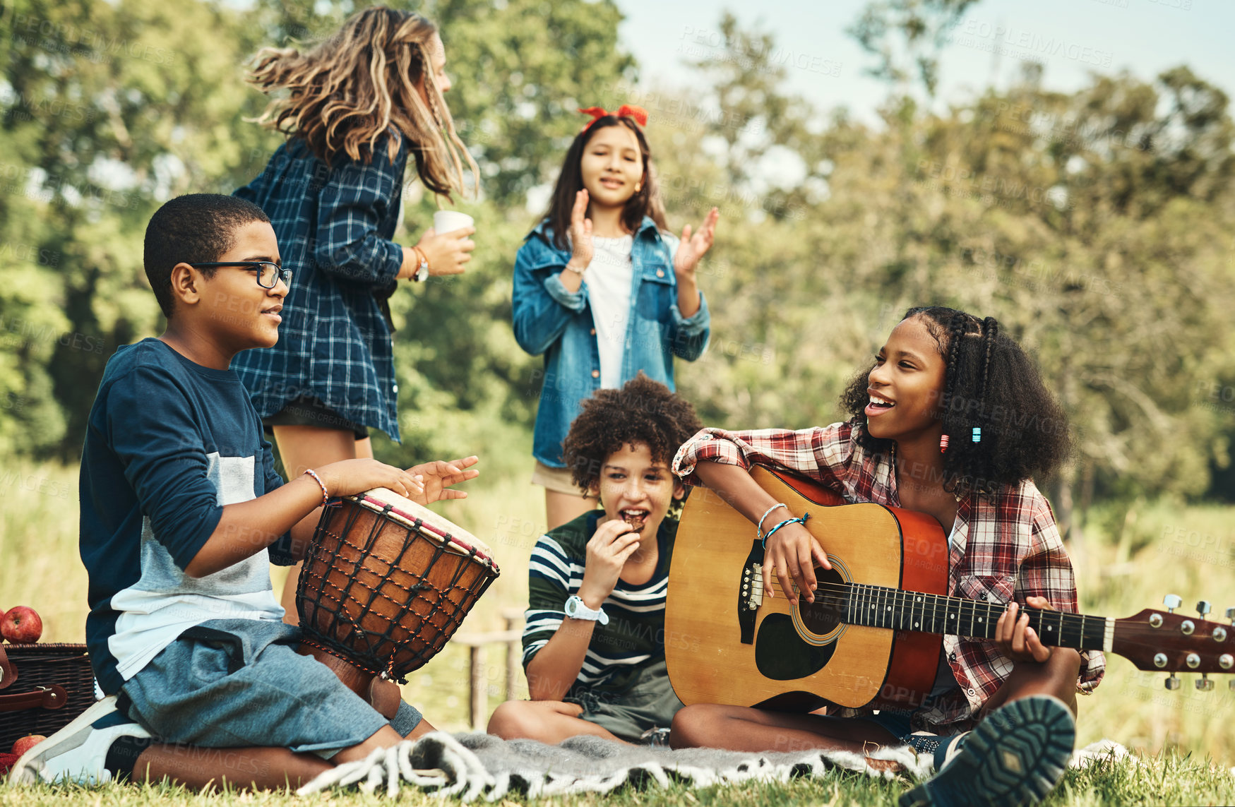 Buy stock photo Shot of a group of teenagers playing musical instruments in nature at summer camp