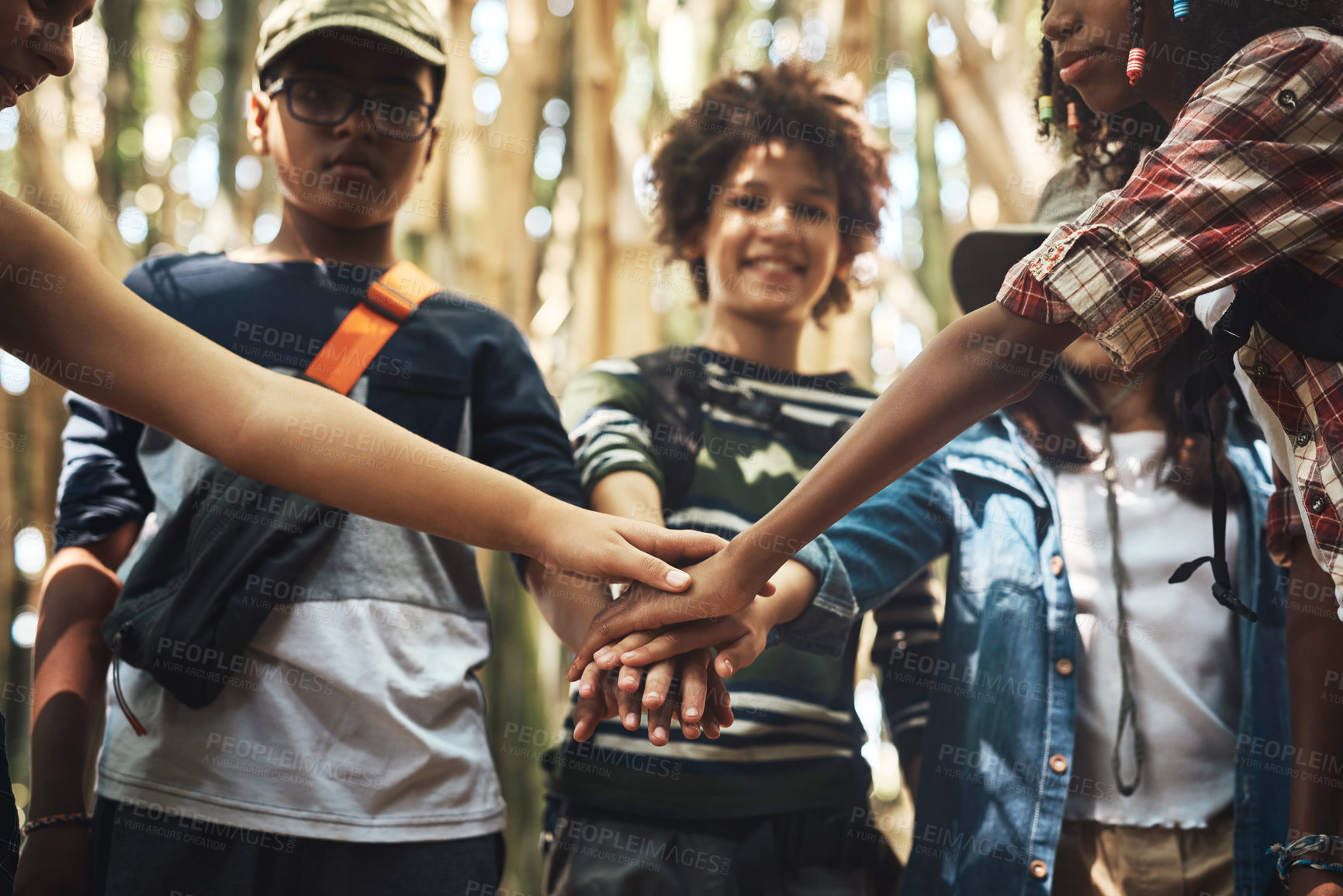 Buy stock photo Shot of a group of teenagers standing in a circle and joining their hands in solidarity at summer camp