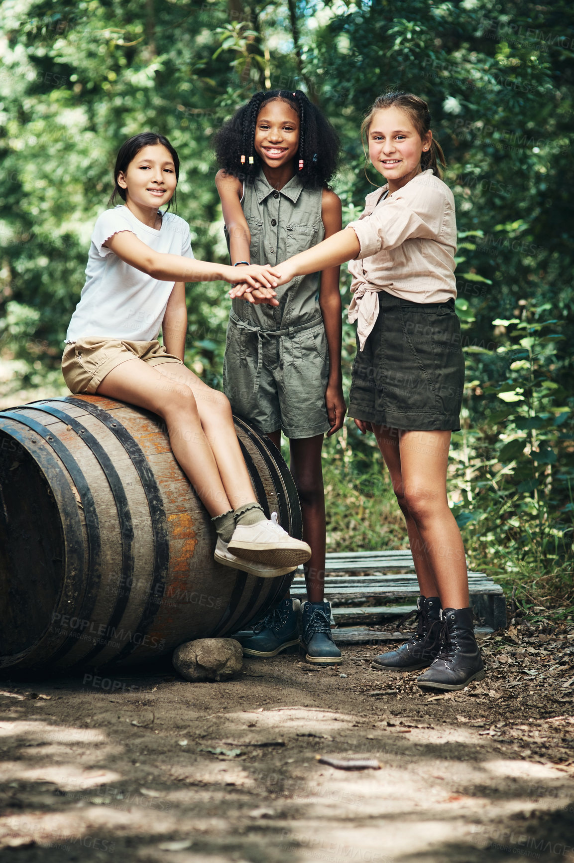 Buy stock photo Shot of a group of teenage girls joining their hands in solidarity at summer camp