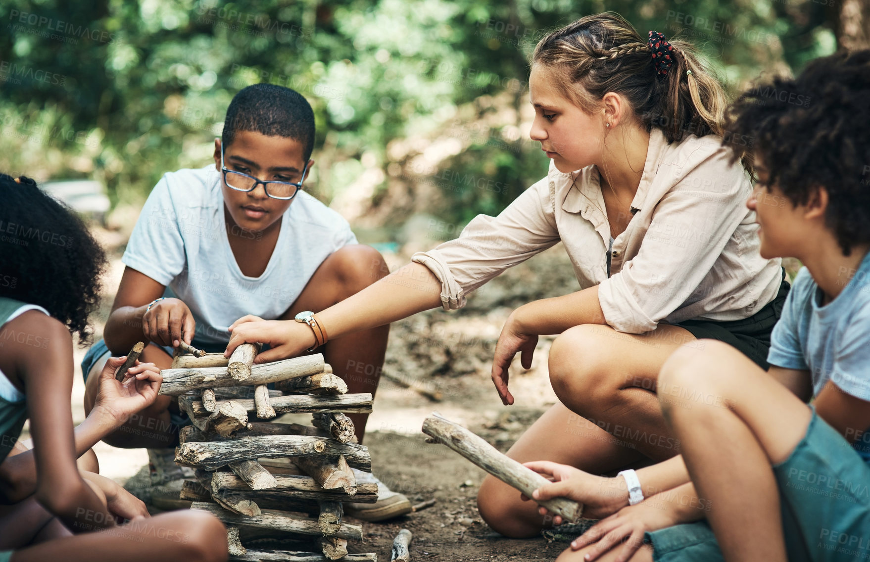 Buy stock photo Shot of a group of teenagers building a pile of wood at summer camp