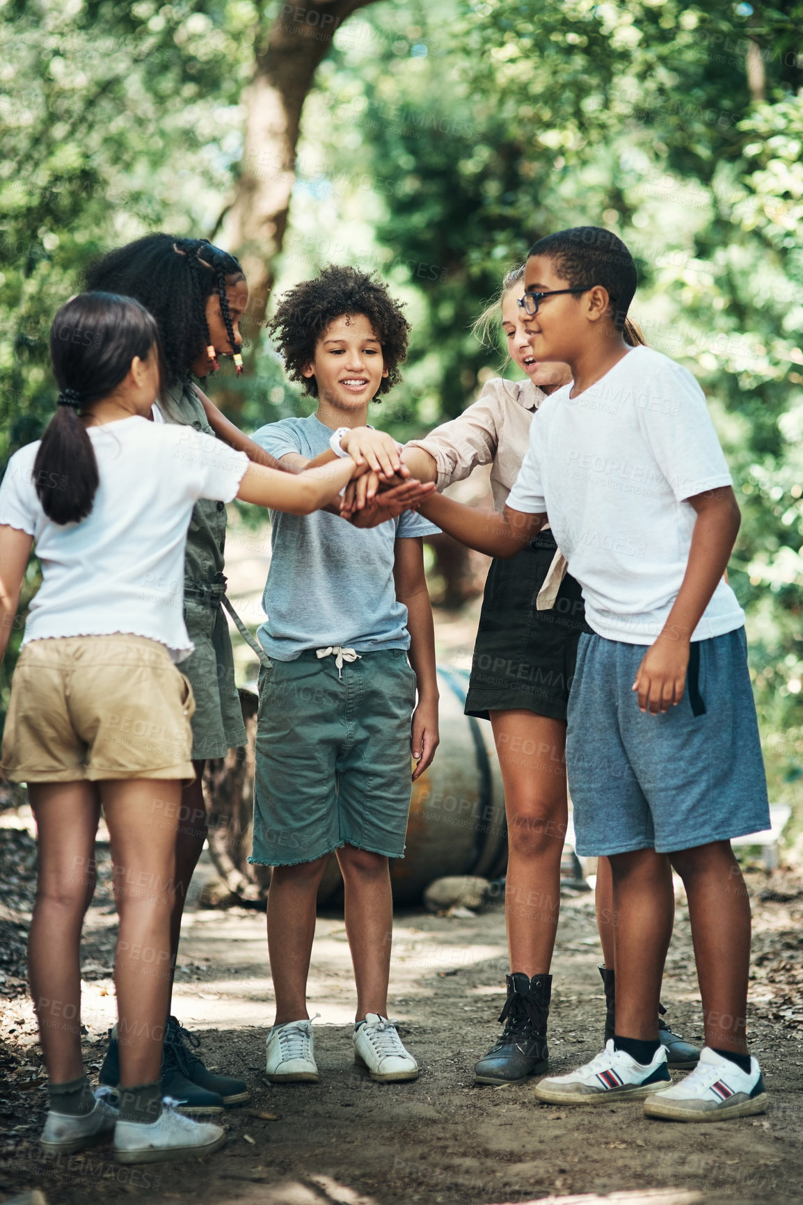 Buy stock photo Shot of a group of teenagers standing in a circle and joining their hands in solidarity at summer camp