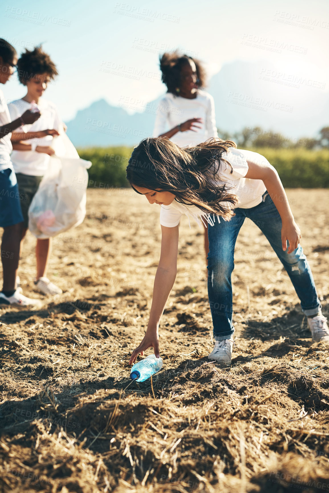 Buy stock photo Shot of a group of teenagers picking up litter off a field at summer camp