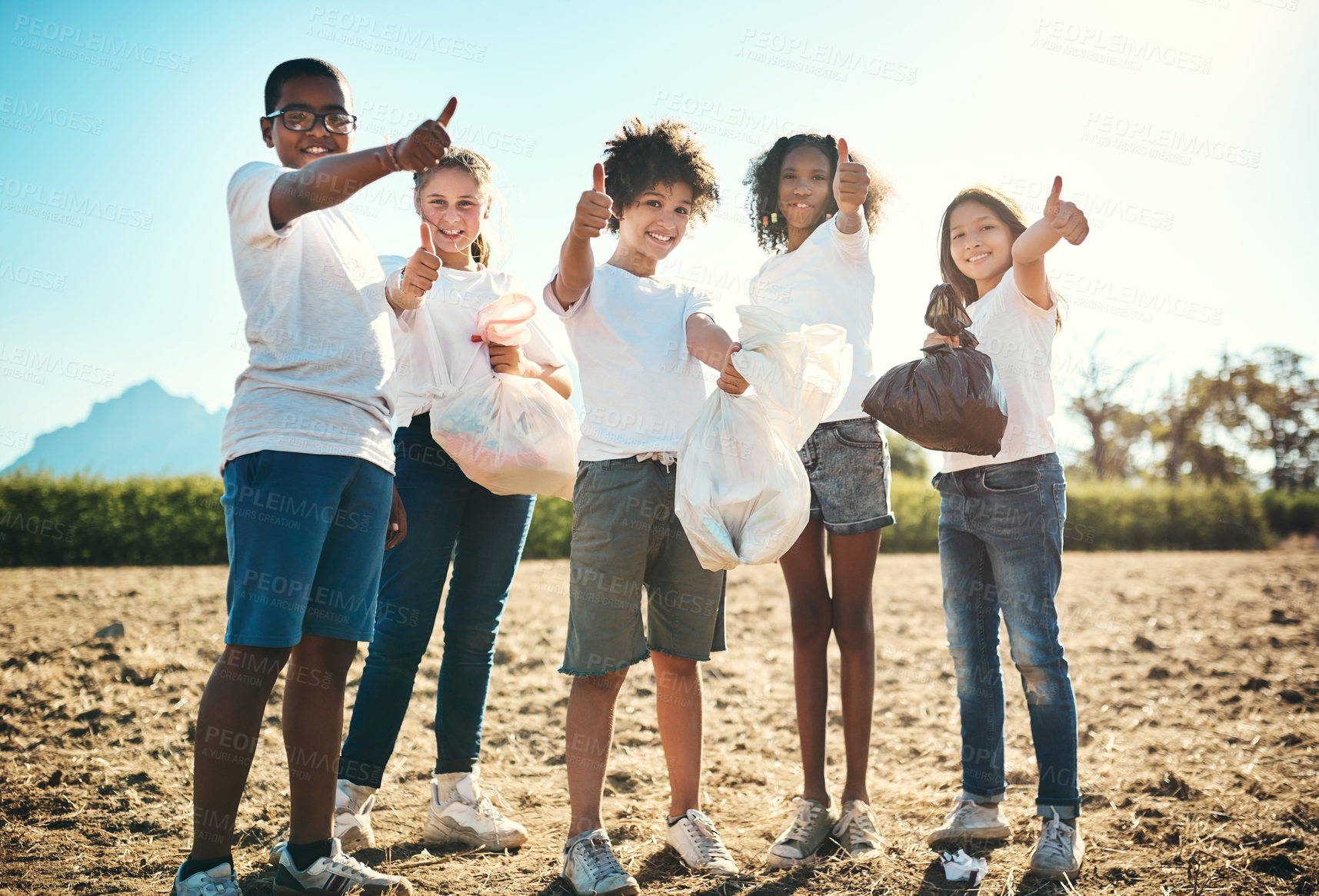 Buy stock photo Shot of a group of teenagers picking up litter off a field and showing thumbs up at summer camp