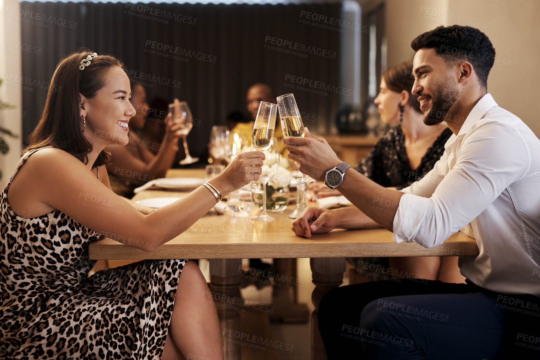 Buy stock photo Shot of a happy young couple sitting together and toasting with champagne during a New Year's dinner party
