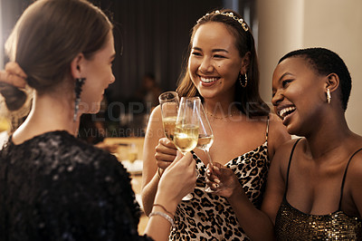 Buy stock photo Shot of a diverse group of friends standing together and toasting with champagne during a New Year's dinner party