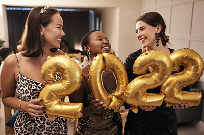 Buy stock photo Shot of a diverse group of friends standing together and holding 2022 balloons during a New Year's dinner party