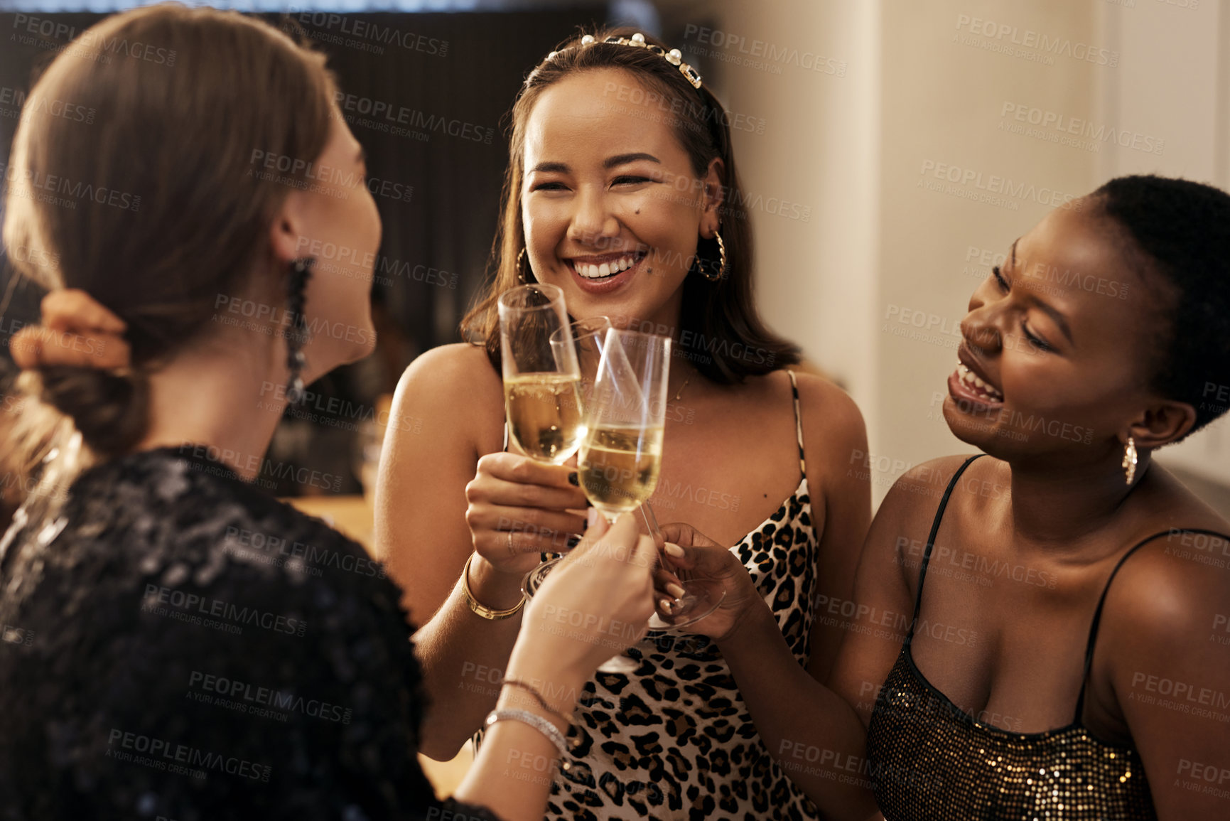 Buy stock photo Shot of a diverse group of friends standing together and toasting with champagne during a New Year's dinner party