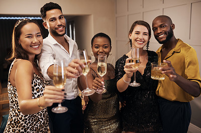 Buy stock photo Shot of a diverse group of friends standing together and holding glasses of champagne during a New Year's dinner party