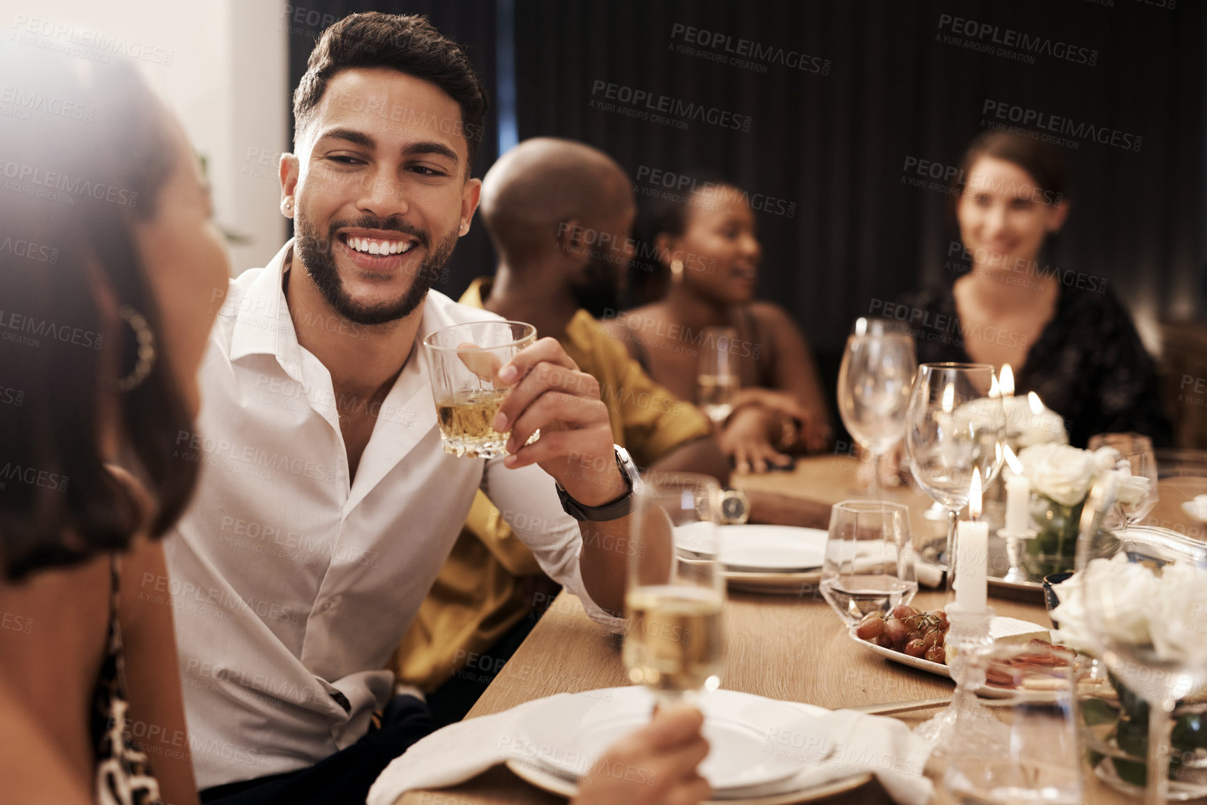 Buy stock photo Shot of a handsome young man sitting and enjoying a New Year's dinner party with friends