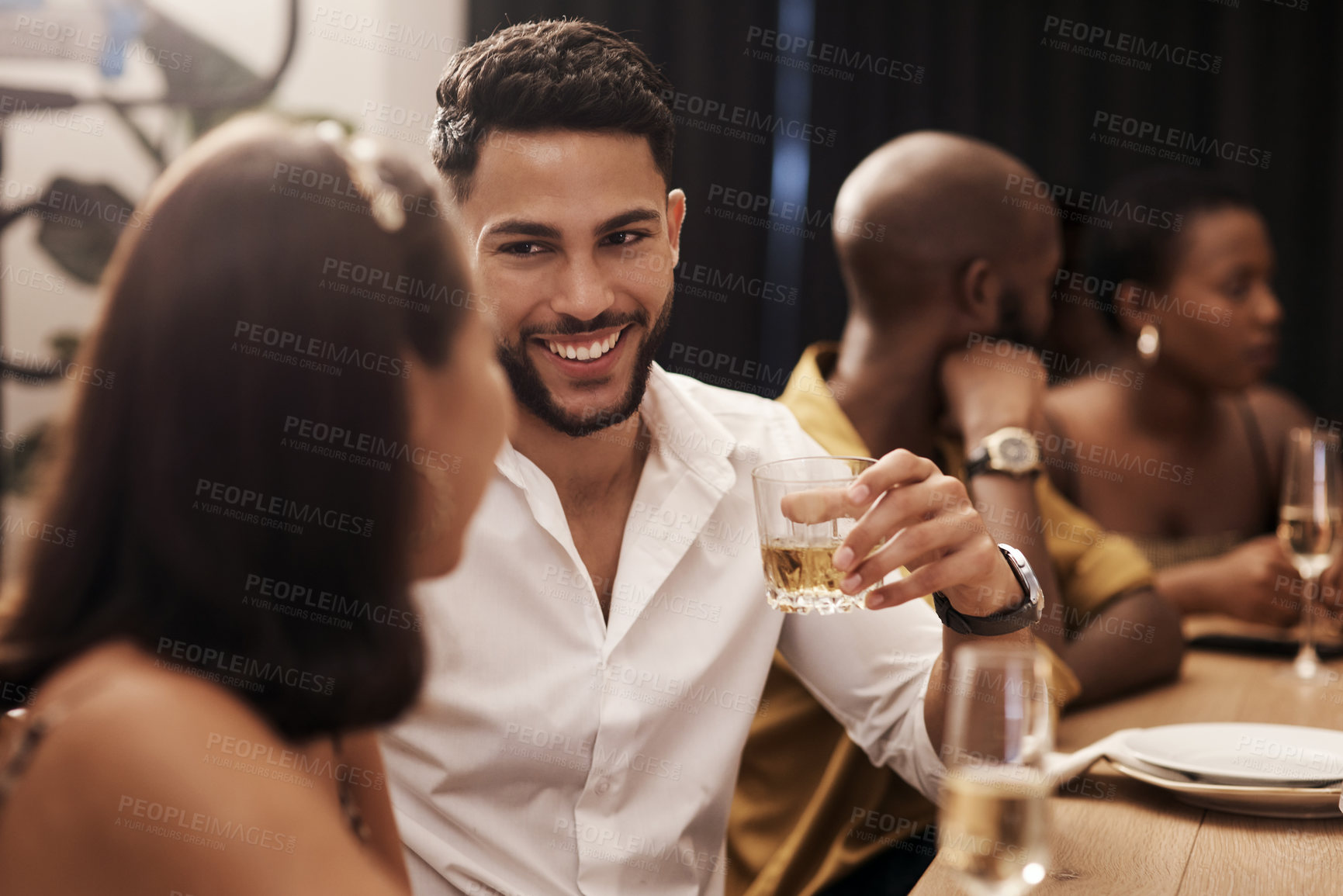 Buy stock photo Shot of a handsome young man sitting and enjoying a New Year's dinner party with friends