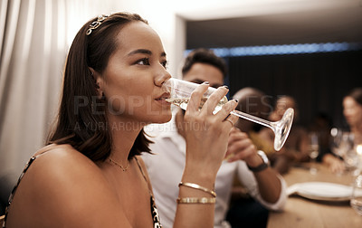 Buy stock photo Shot of an attractive young woman sitting and drinking champagne at a New Year's dinner party with friends
