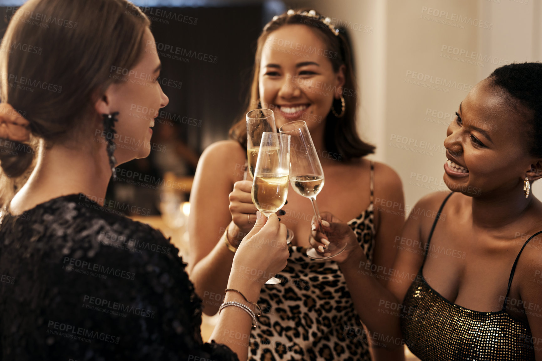 Buy stock photo Shot of a diverse group of friends standing together and toasting with champagne during a New Year's dinner party