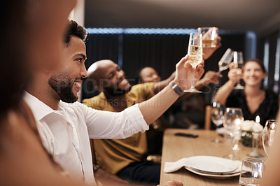 Buy stock photo Shot of a diverse group of friends sitting together and toasting with champagne during a New Year's dinner party