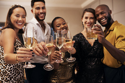 Buy stock photo Shot of a diverse group of friends standing together and holding glasses of champagne during a New Year's dinner party