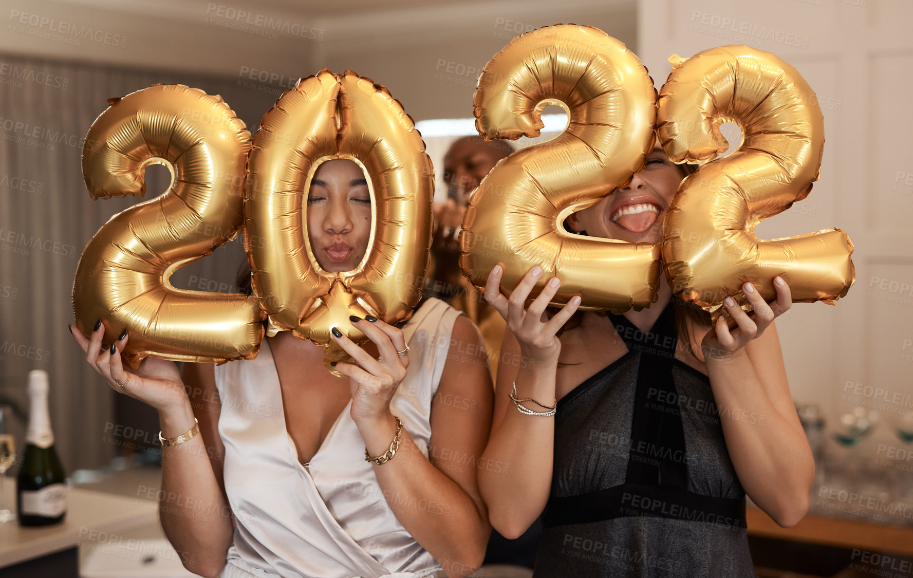 Buy stock photo Shot of a diverse group of friends standing together and holding up 2022 balloons during a New Year's party
