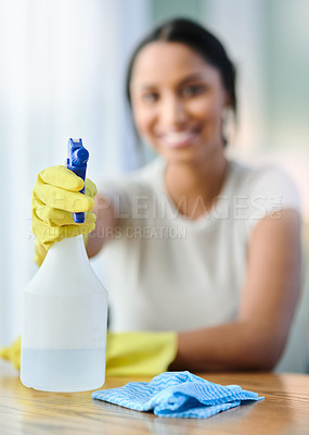 Buy stock photo Shot of a young woman holding a spray bottle at home