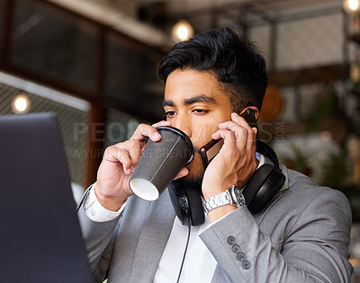 Buy stock photo Shot of a young businessman drinking coffee while using a phone and laptop at a cafe