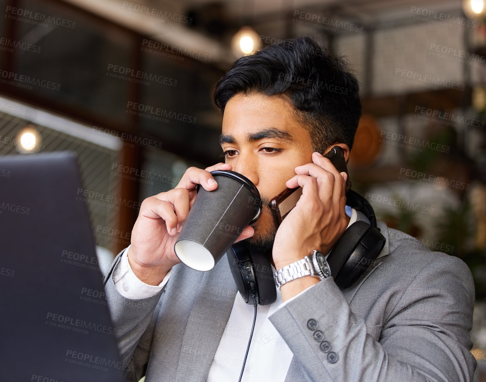 Buy stock photo Shot of a young businessman drinking coffee while using a phone and laptop at a cafe