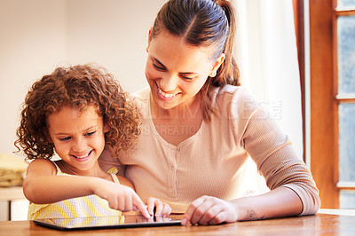 Buy stock photo Shot of a young mother using a digital tablet together