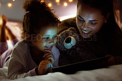 Buy stock photo Shot of a mother and daughter using a digital tablet before bed time