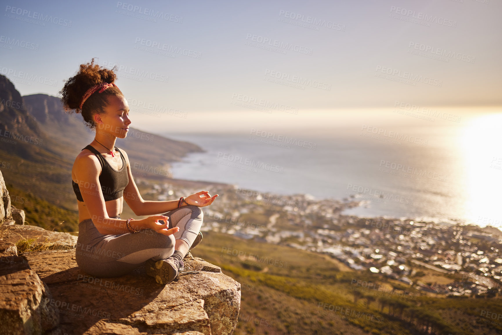 Buy stock photo Shot of a young woman meditating while sitting on a mountain cliff