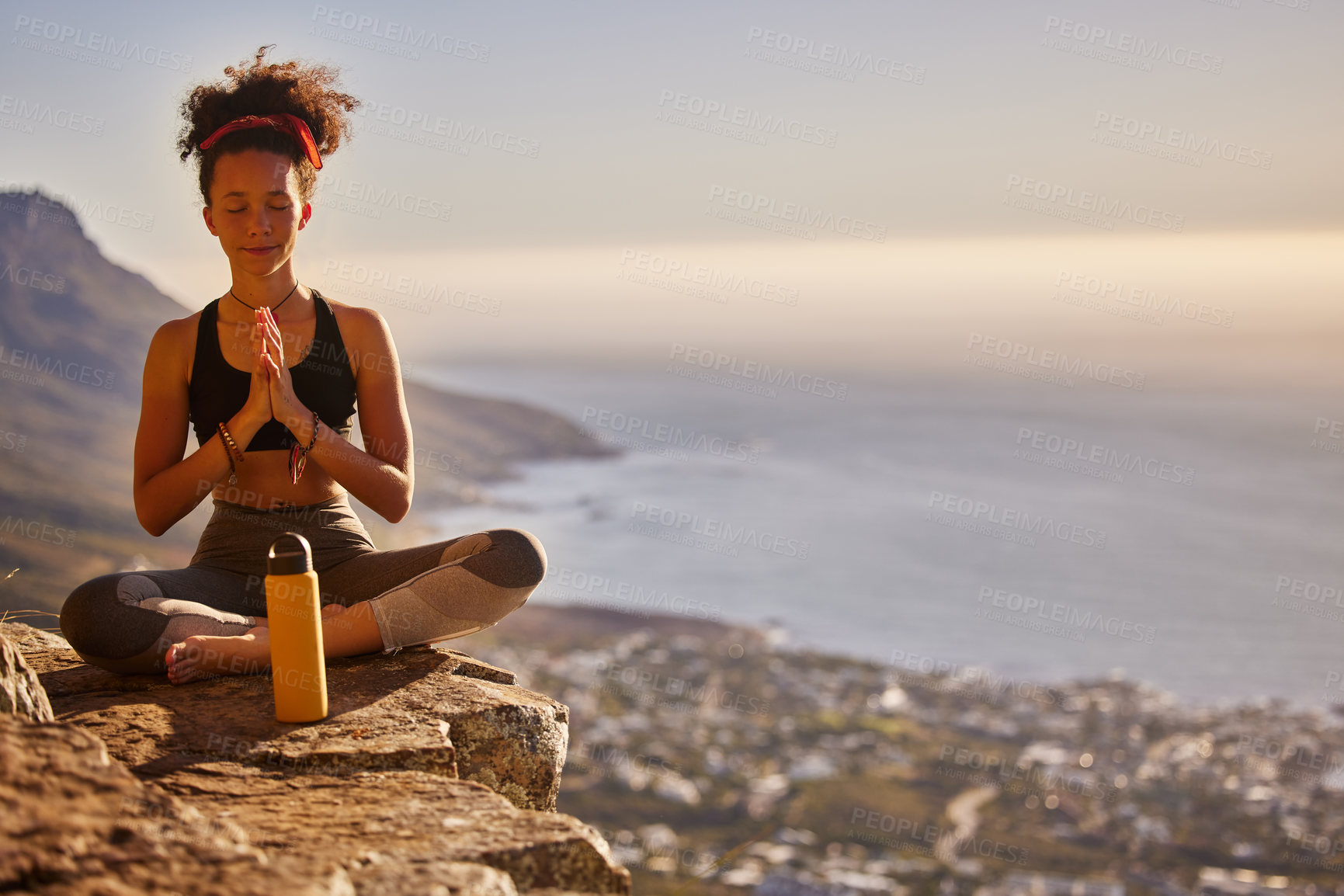 Buy stock photo Shot of a young woman meditating while sitting on a mountain cliff