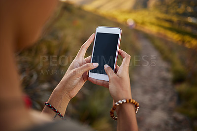 Buy stock photo Cropped shot of a woman using her cellphone while out on a hike