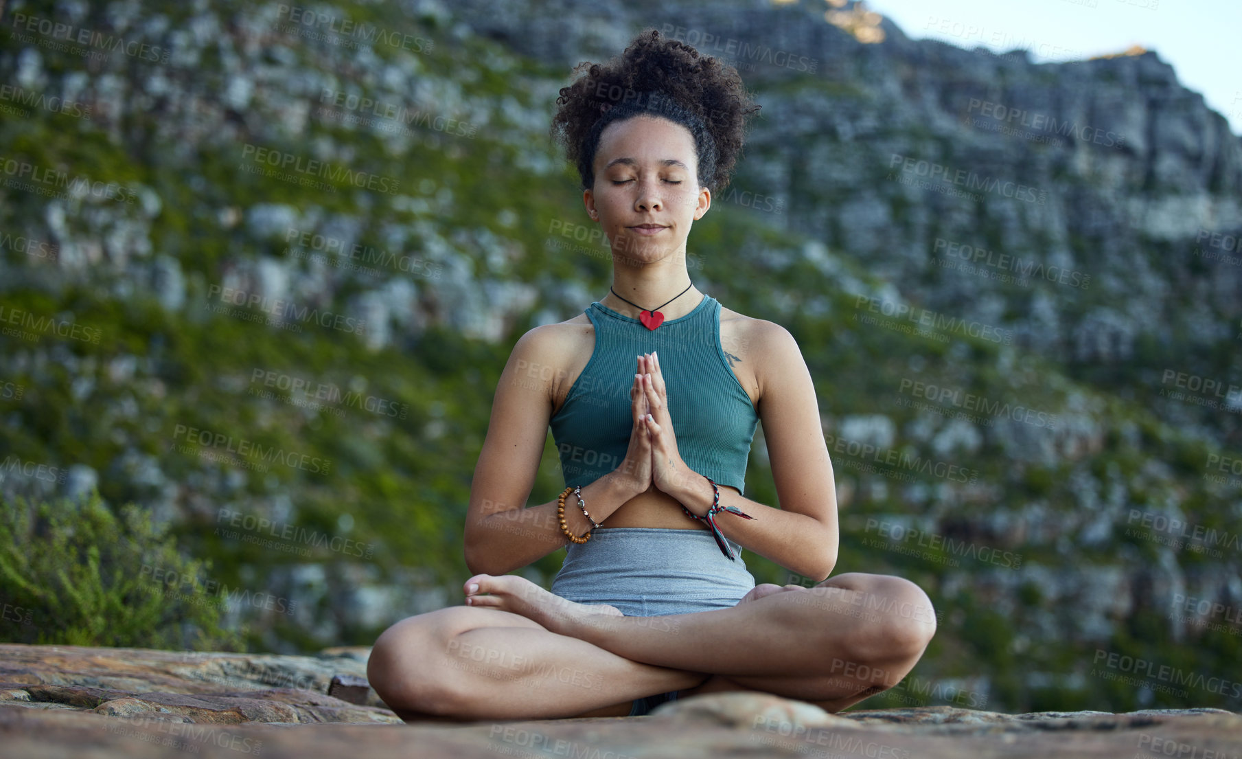 Buy stock photo Shot of a young woman meditating while out in the mountains