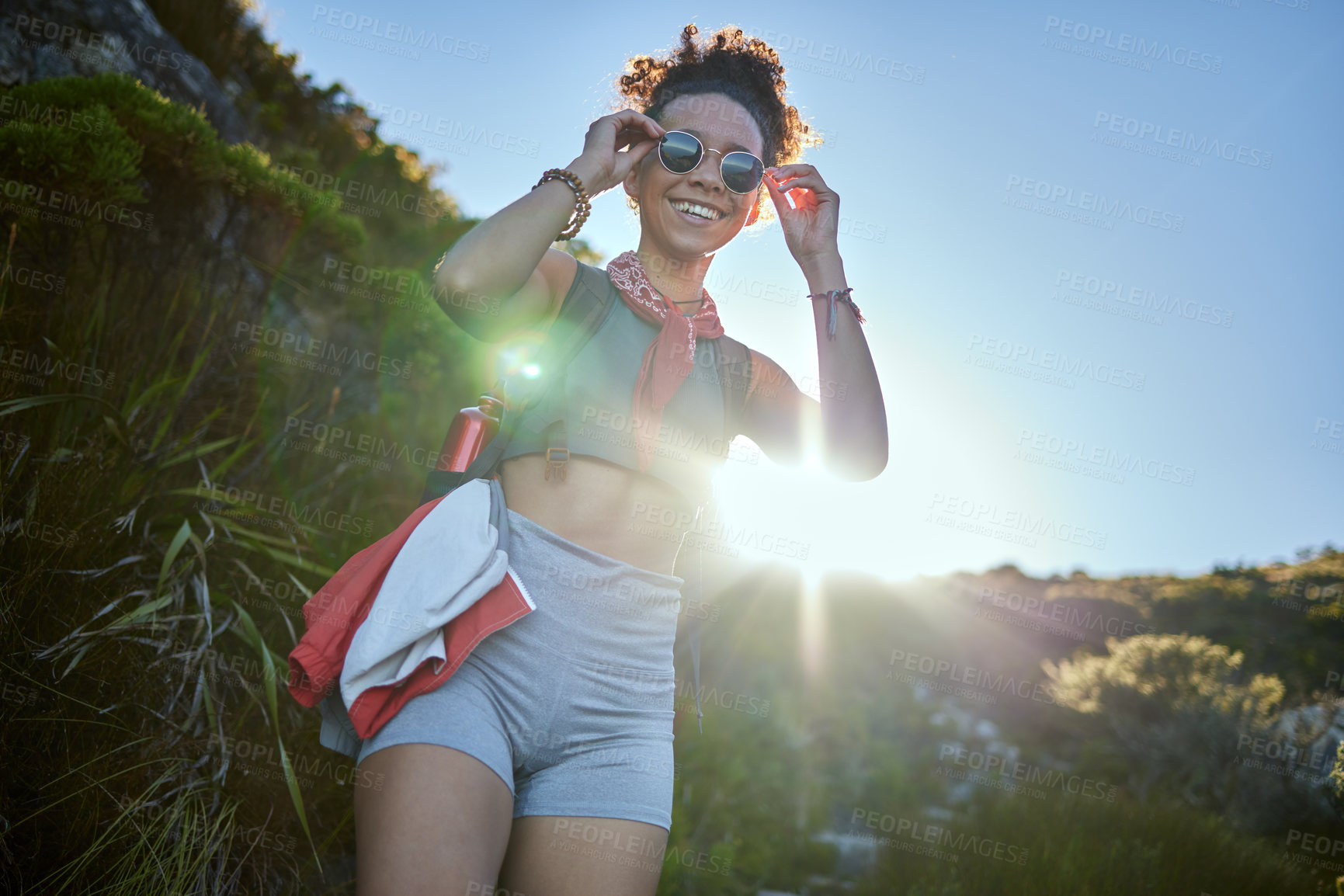 Buy stock photo Shot of a young woman wearing her sunglasses while out on a hike