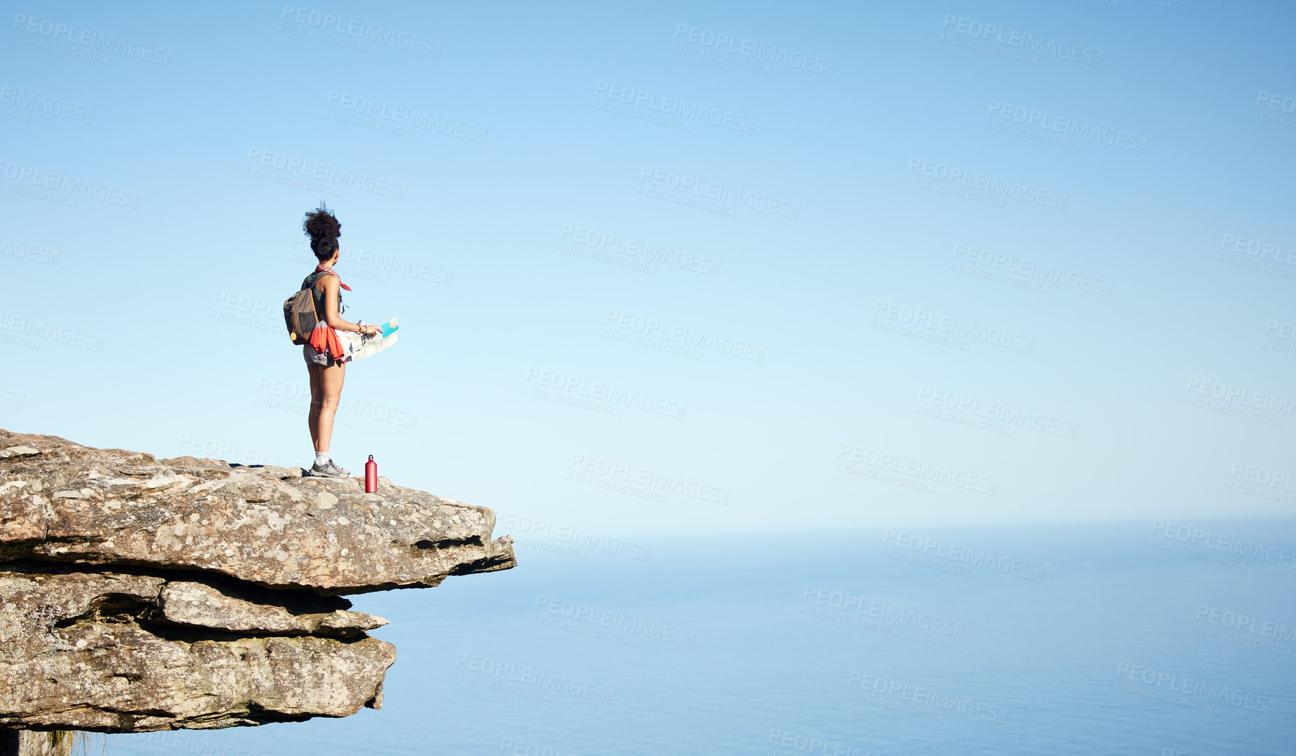 Buy stock photo Shot of a woman holding a map while standing on a mountain cliff