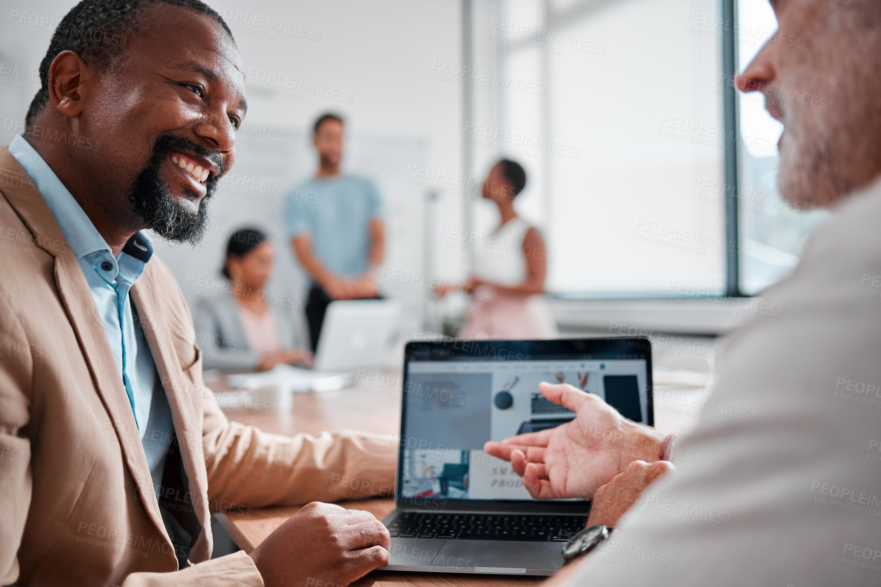 Buy stock photo Cropped shot of two handsome mature businessmen talking in the boardroom during a meeting with their colleagues in the background