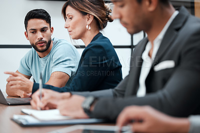 Buy stock photo Cropped shot of two young businesspeople talking in the boardroom during a meeting with their colleagues