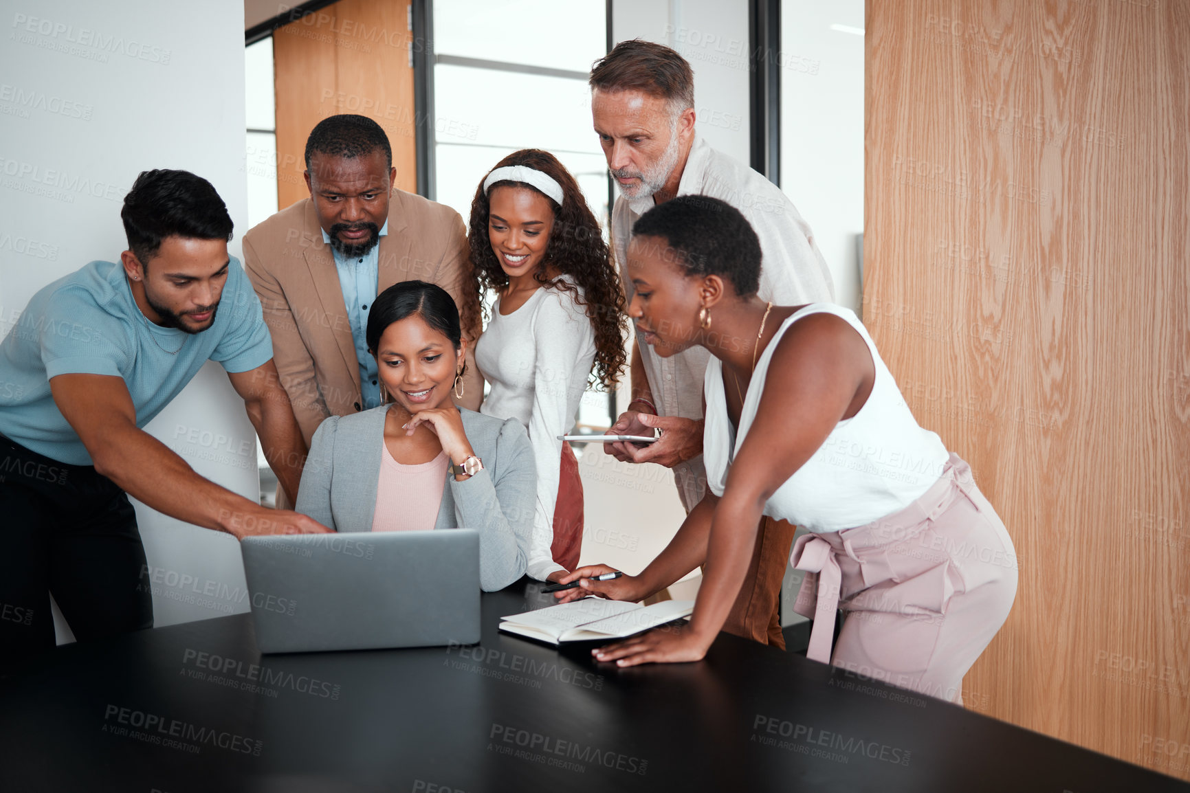 Buy stock photo Shot of a group of businesspeople gathered around their manager using a laptop