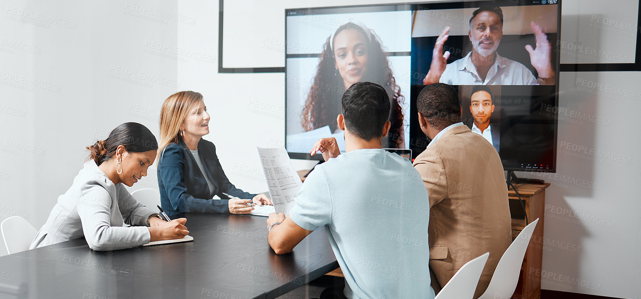 Buy stock photo Cropped shot of a diverse group of businesspeople sitting in the boardroom during a meeting with their international colleagues via video chat