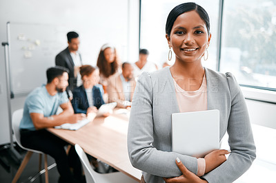 Buy stock photo Cropped portrait of an attractive young businesswoman attending a meeting in the boardroom with her colleagues in the background