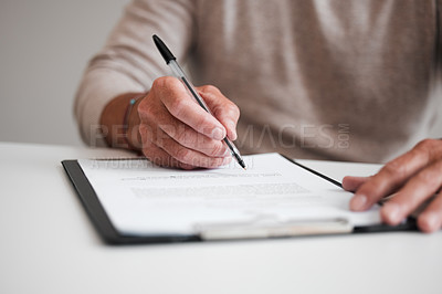 Buy stock photo Cropped shot of an unrecognizable businessman filling out a form on a clipboard while sitting at his desk in the office