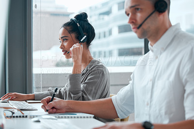 Buy stock photo Shot of two young businesspeople working together in a call center