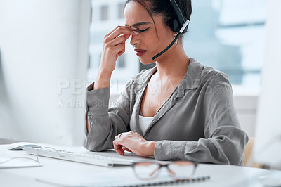 Buy stock photo Shot of a young female businesswoman working in a call center with a headache