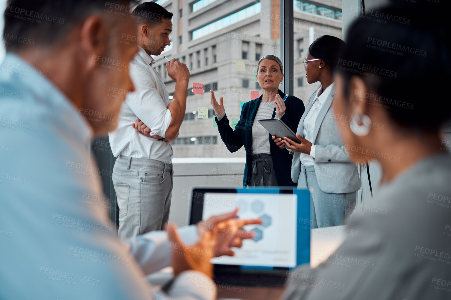 Buy stock photo Shot of a group of businesspeople brainstorming with notes on a window in an office