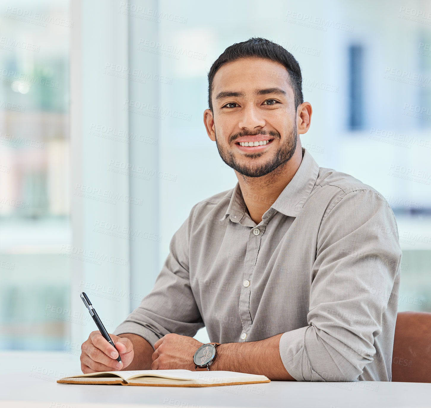 Buy stock photo Shot of a young businessman making notes in his notebook