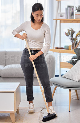 Buy stock photo Shot of a young woman sweeping the floor at home