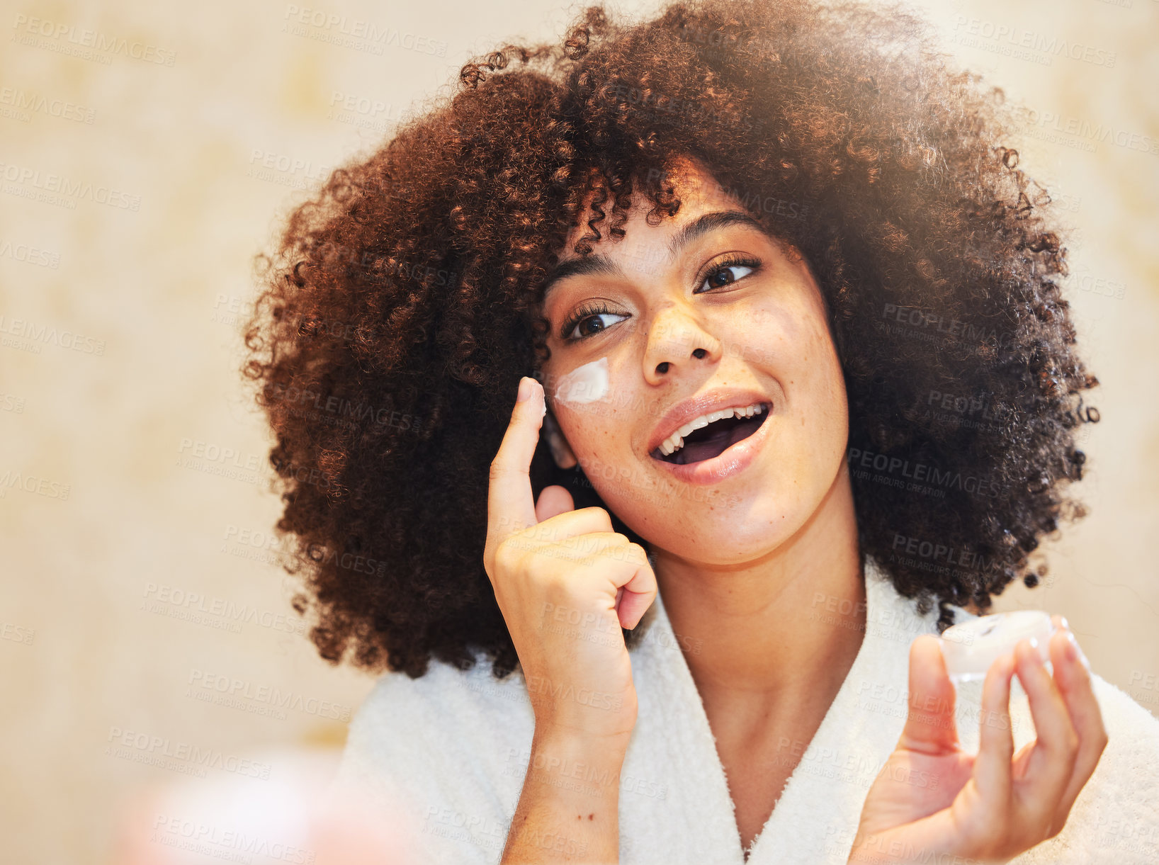 Buy stock photo Shot of a beautiful young woman applying moisturiser to her face