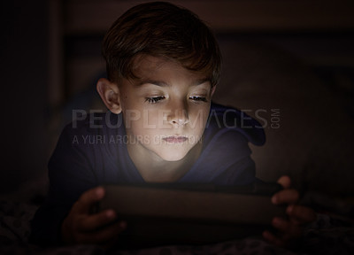 Buy stock photo Tablet, relax and boy child in dark watching movie, film or show online for entertainment at home. Light, night and young kid streaming video on internet with digital technology in bedroom at house.