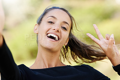 Buy stock photo Cropped portrait of an attractive and athletic young woman gesturing peace while standing outdoors