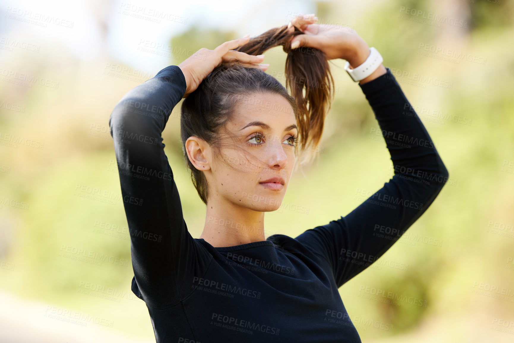 Buy stock photo Cropped shot of an attractive and athletic young woman tying her hair back while standing outdoors