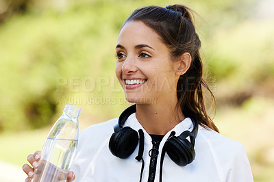 Buy stock photo Cropped shot of an attractive and athletic young woman drinking water while standing outdoors