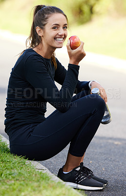 Buy stock photo Full length portrait of an attractive and athletic young woman sitting on the curb with her apple and water bottle