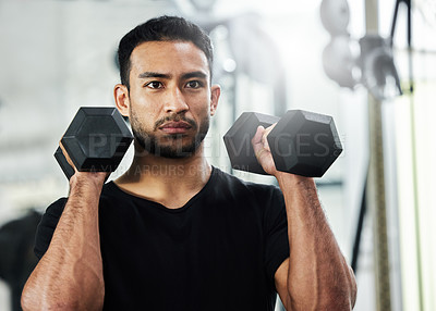 Buy stock photo Shot of a handsome young man working out with dumbbells at the gym