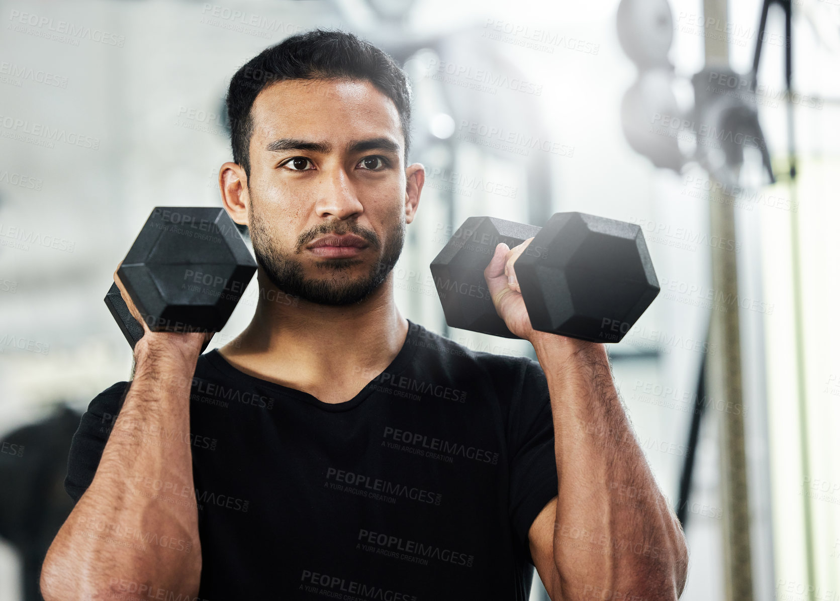 Buy stock photo Shot of a handsome young man working out with dumbbells at the gym