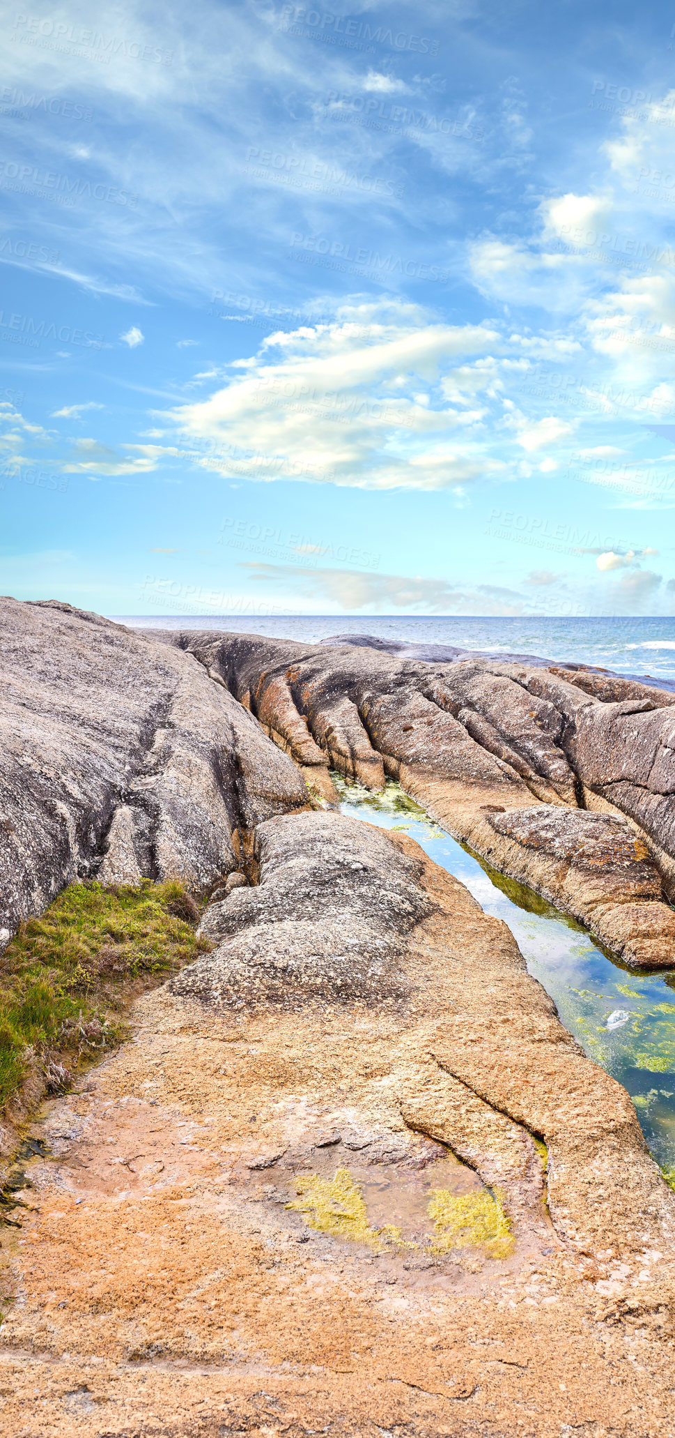 Buy stock photo Big boulders at a beach shore against a cloudy blue sky background with copy space. Calm and majestic ocean across the horizon and rocky coast. Beautiful and scenic landscape of a peaceful sea 